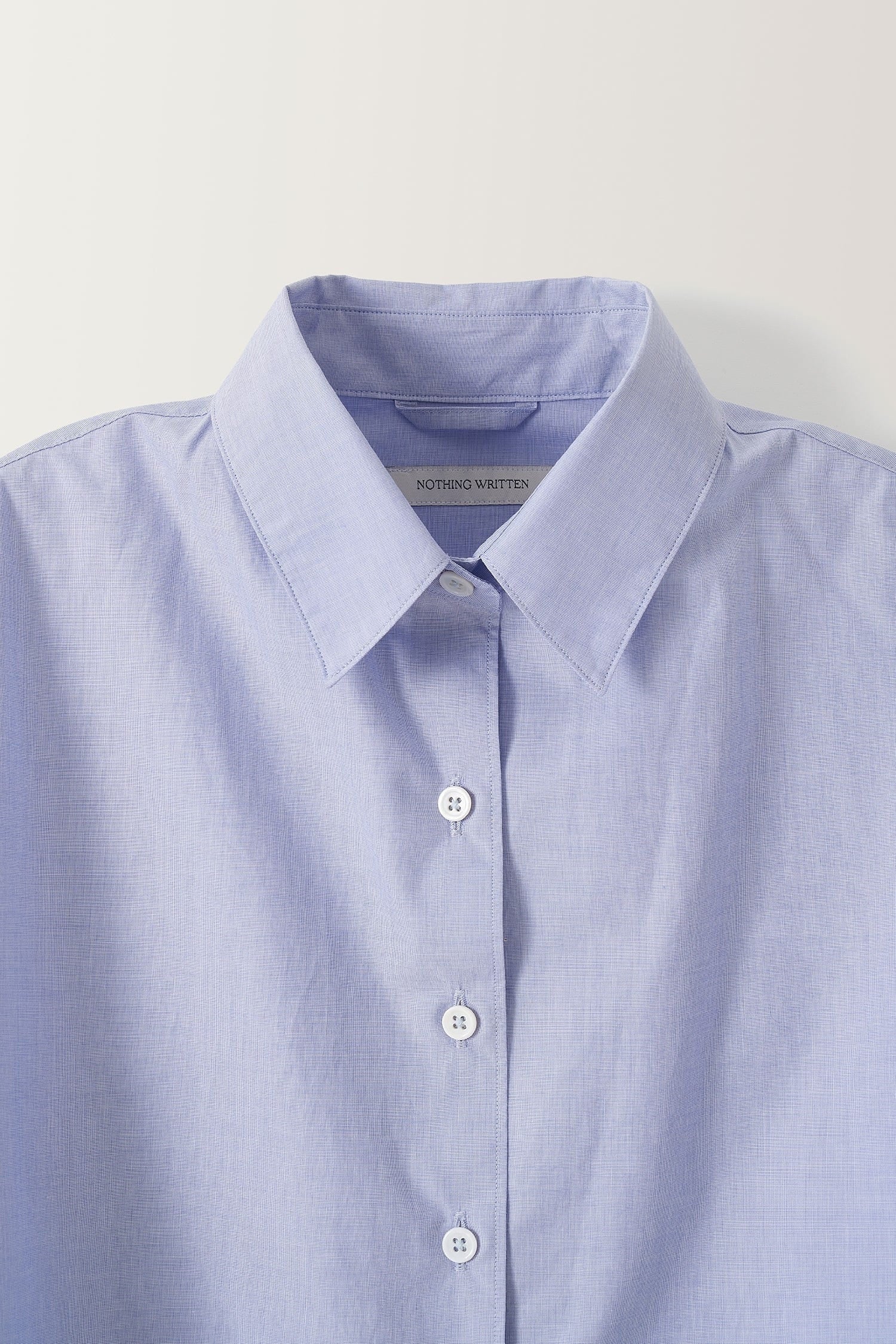 Detail of classic pointed collar and front buttons on Nothing Written light blue cotton shirt