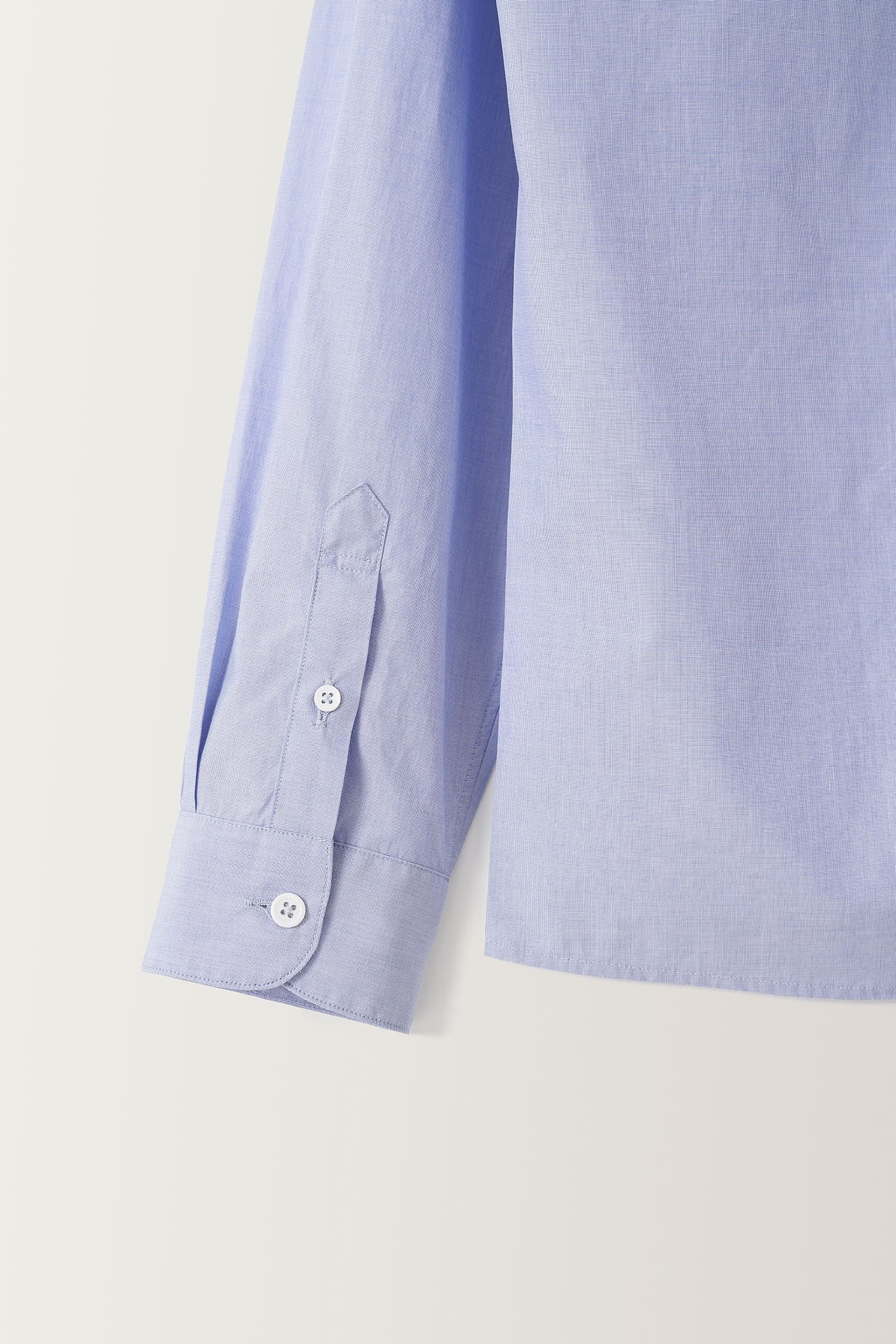 Detail of cuff and button finish on Nothing Written light blue fitted cotton shirt