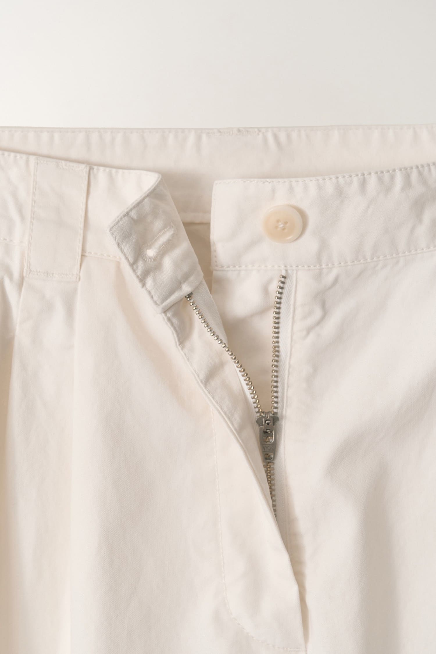 Detail of button and zip closure on Nothing Written Lena Tuck pants white