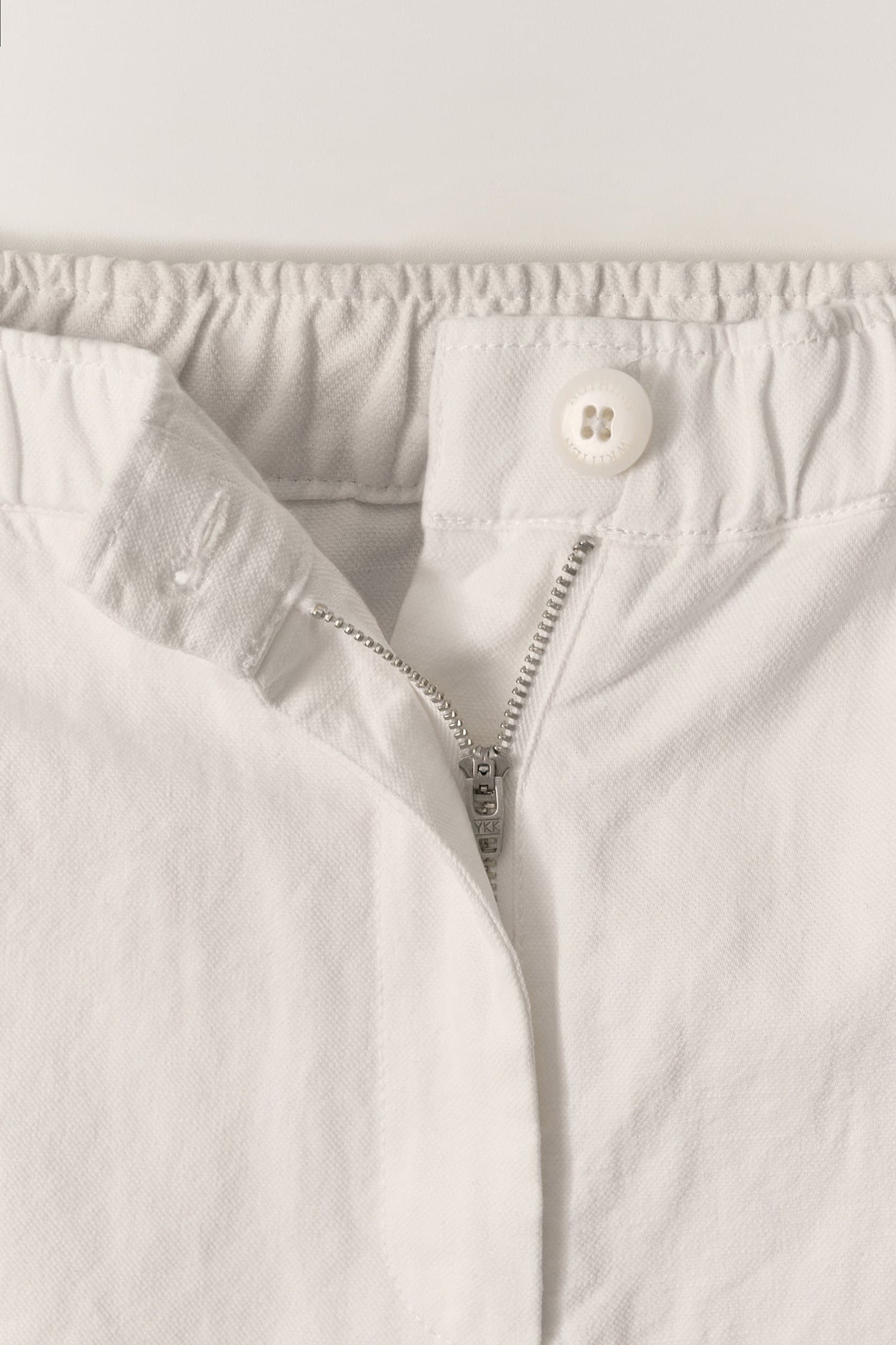 Detail of elastic waistband and button on Nothing Written Linen Shorts white