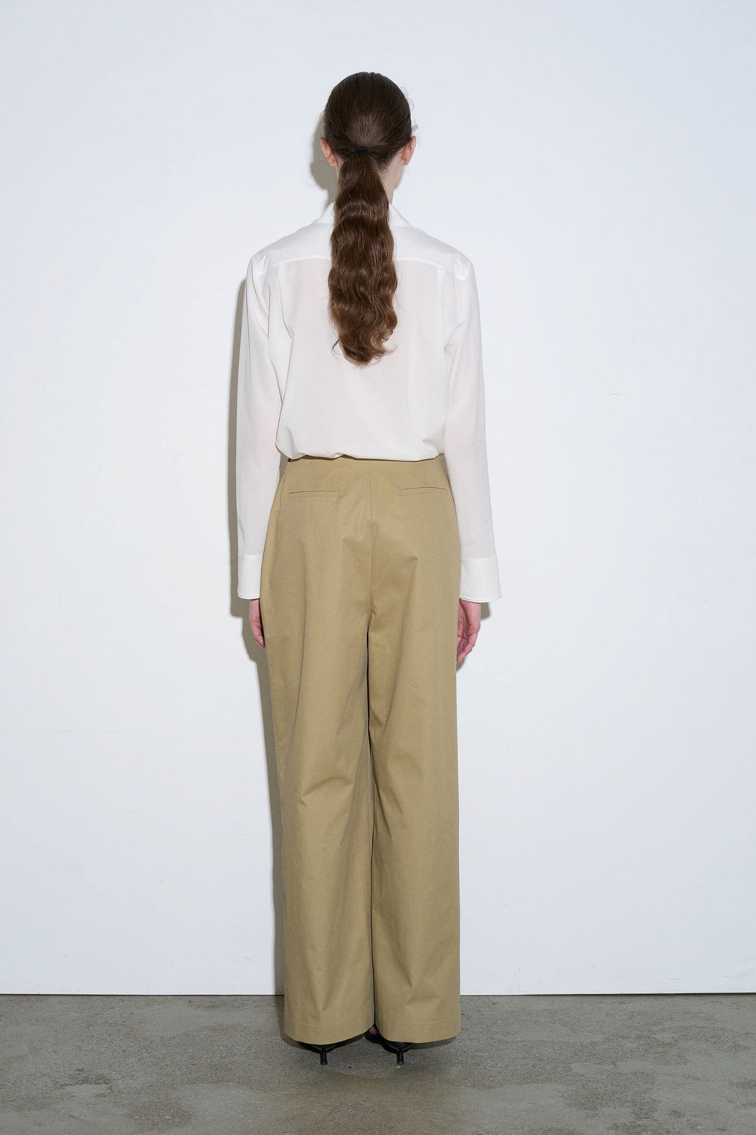 The Loom beige asymmetrical wrap trousers back view with tailored waistband and wide leg fit