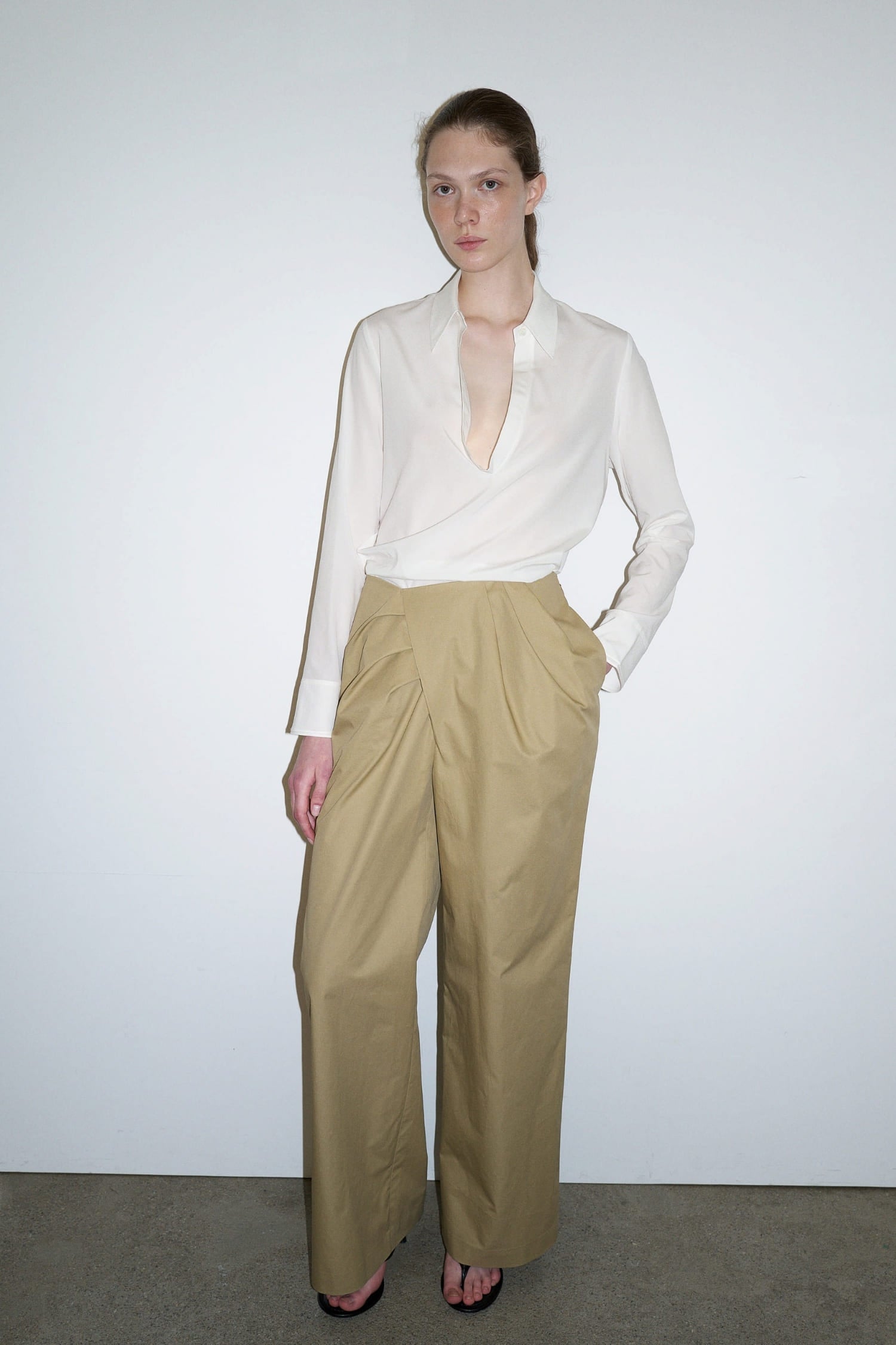 The Loom beige wrap trousers styled with white blouse showing asymmetric front panel and soft drape