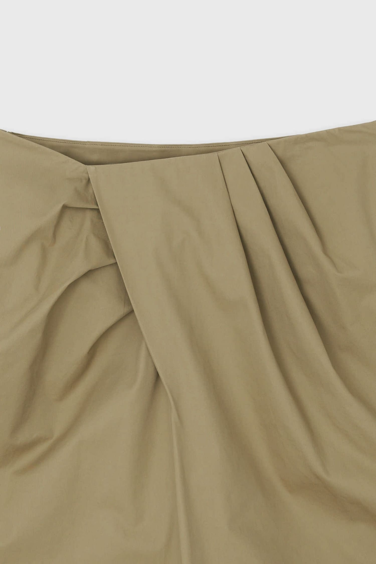 Close-up of asymmetric pleated wrap detail on The Loom beige trousers