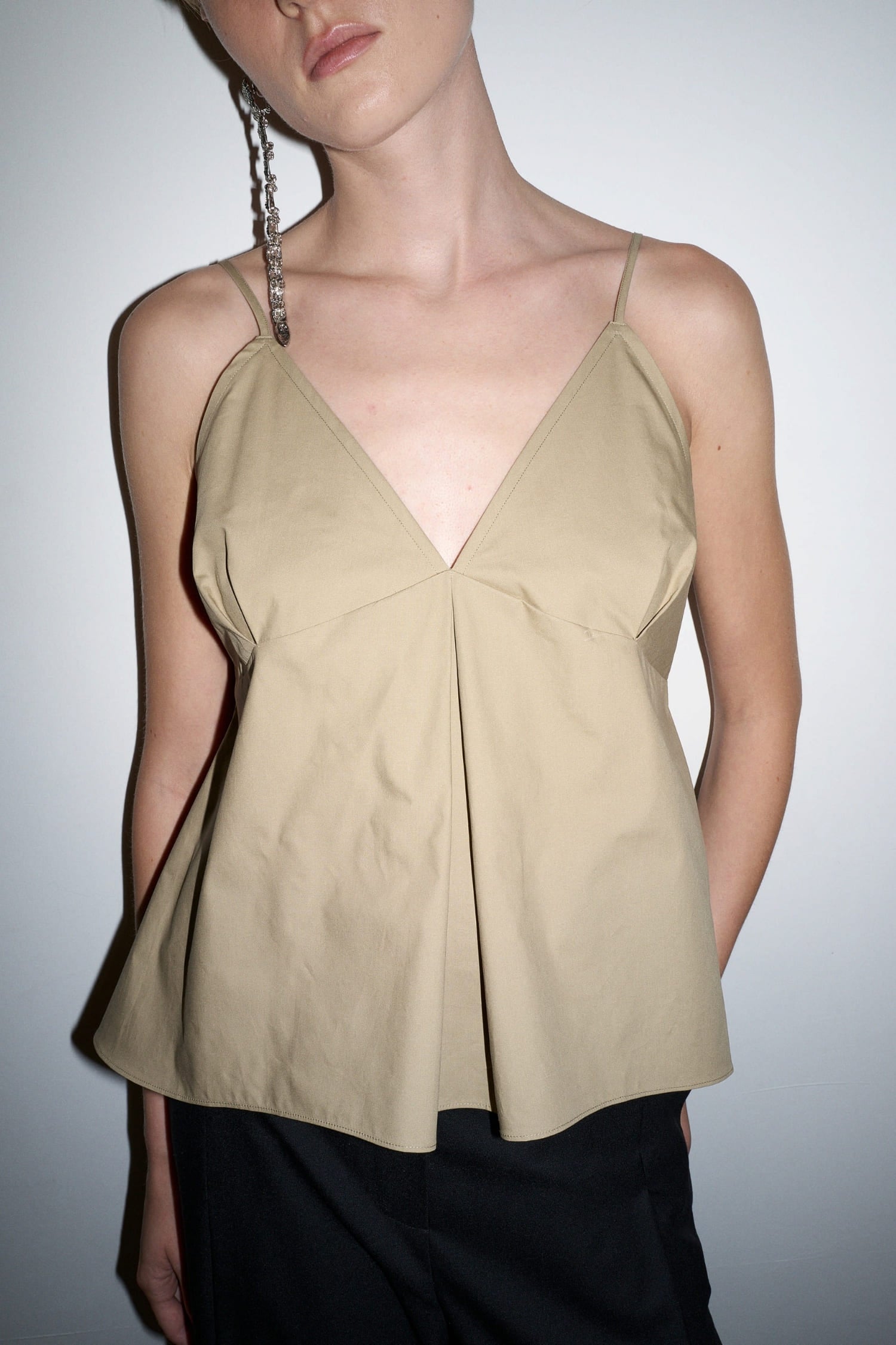 The Loom beige cotton camisole close-up showing V neckline and front pleat detail
