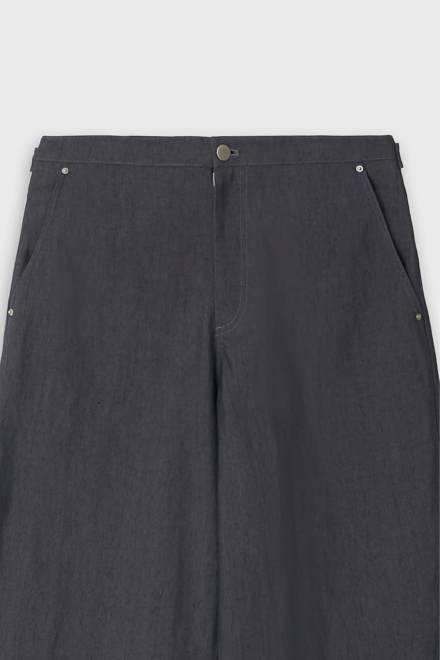 Close-up of waistband and front button closure on The Loom indigo denim trousers