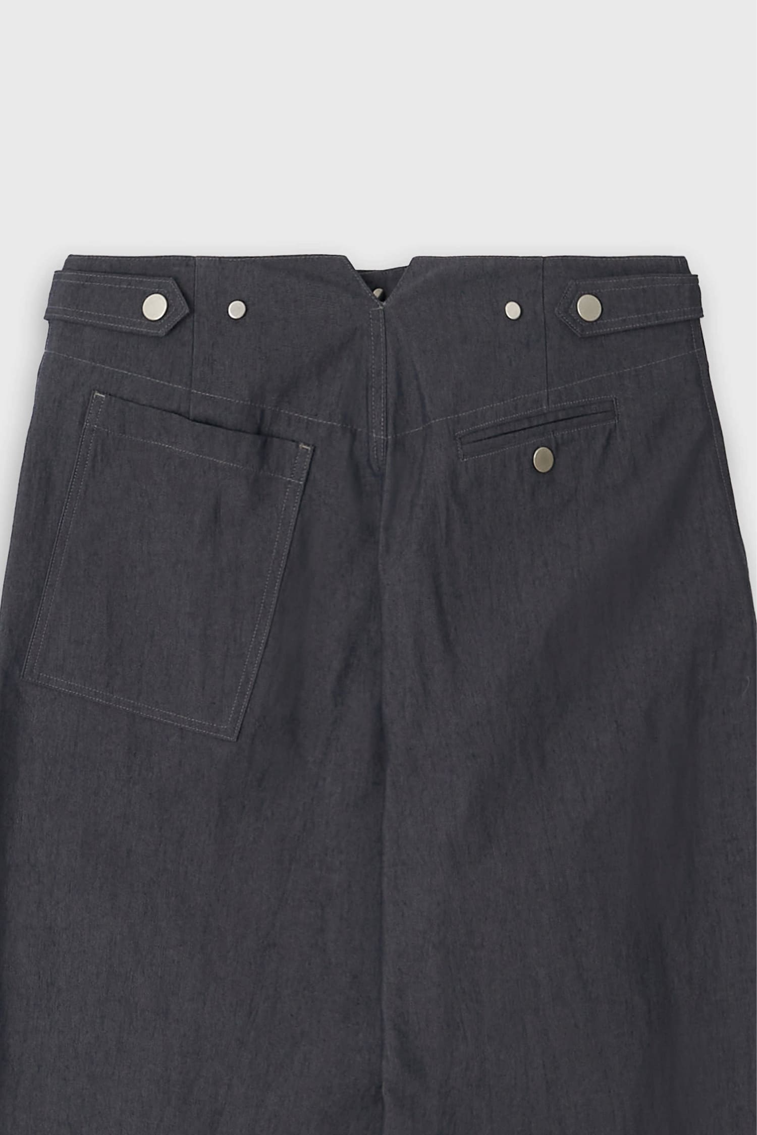 Detail of back pocket and metal button accents on The Loom indigo denim barrel trousers
