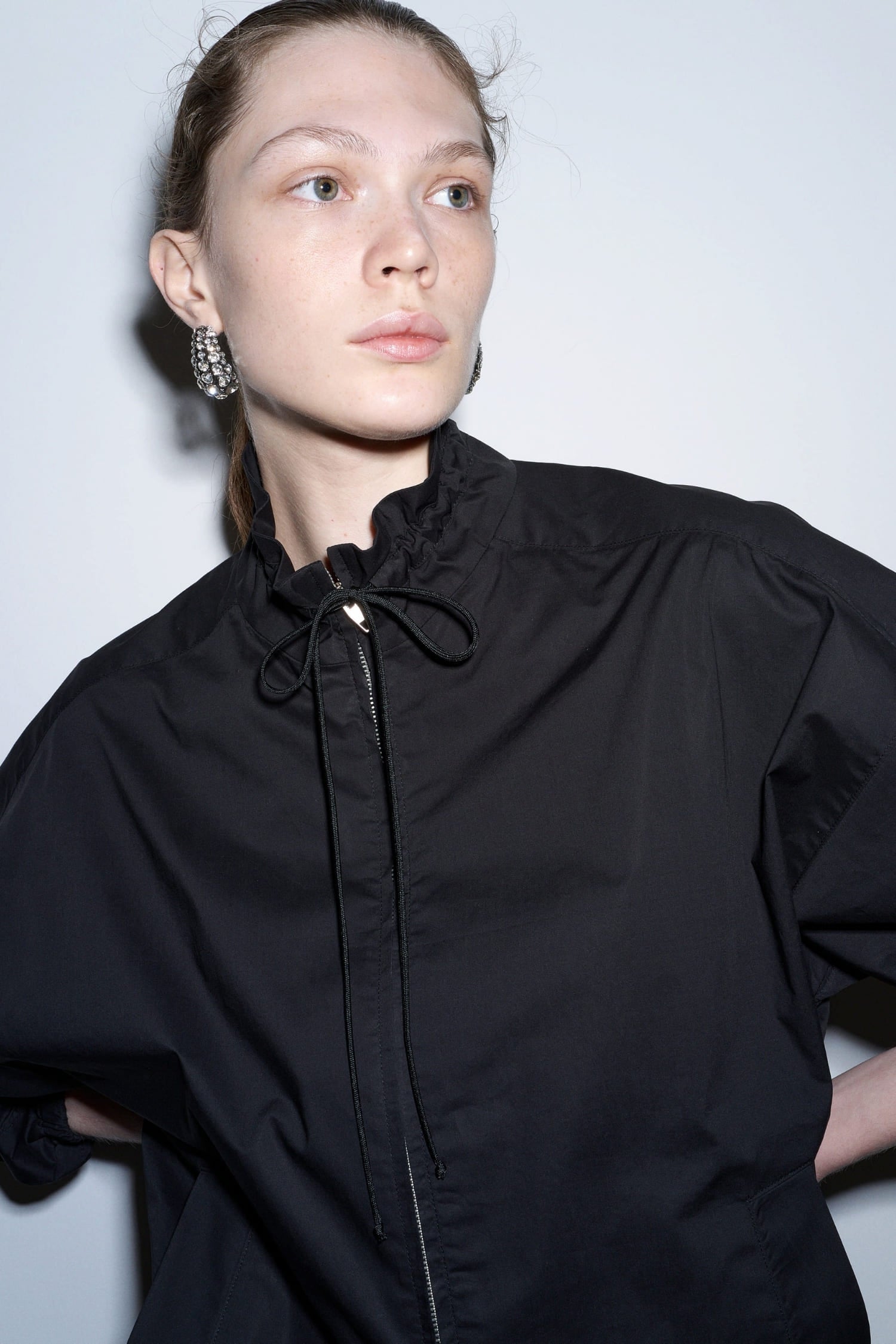 The Loom black jacket close-up showing gathered drawstring neckline and front zipper detail