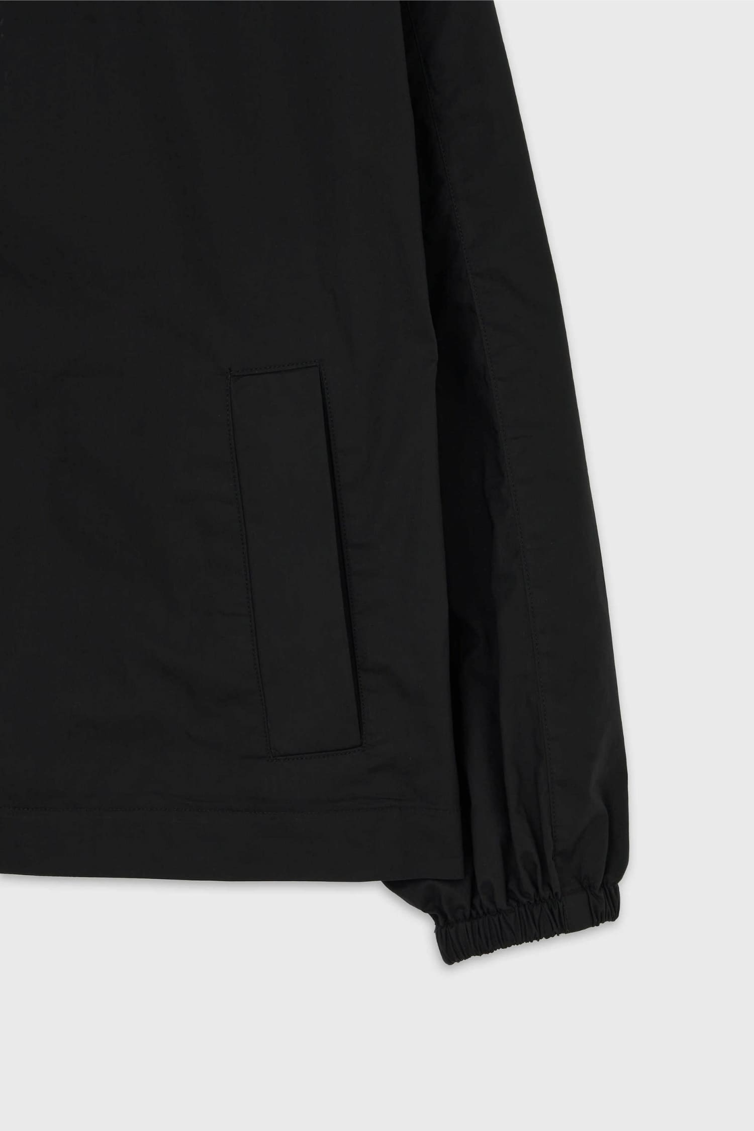 Detail of elastic cuff and front patch pocket on The Loom black drawstring jacket