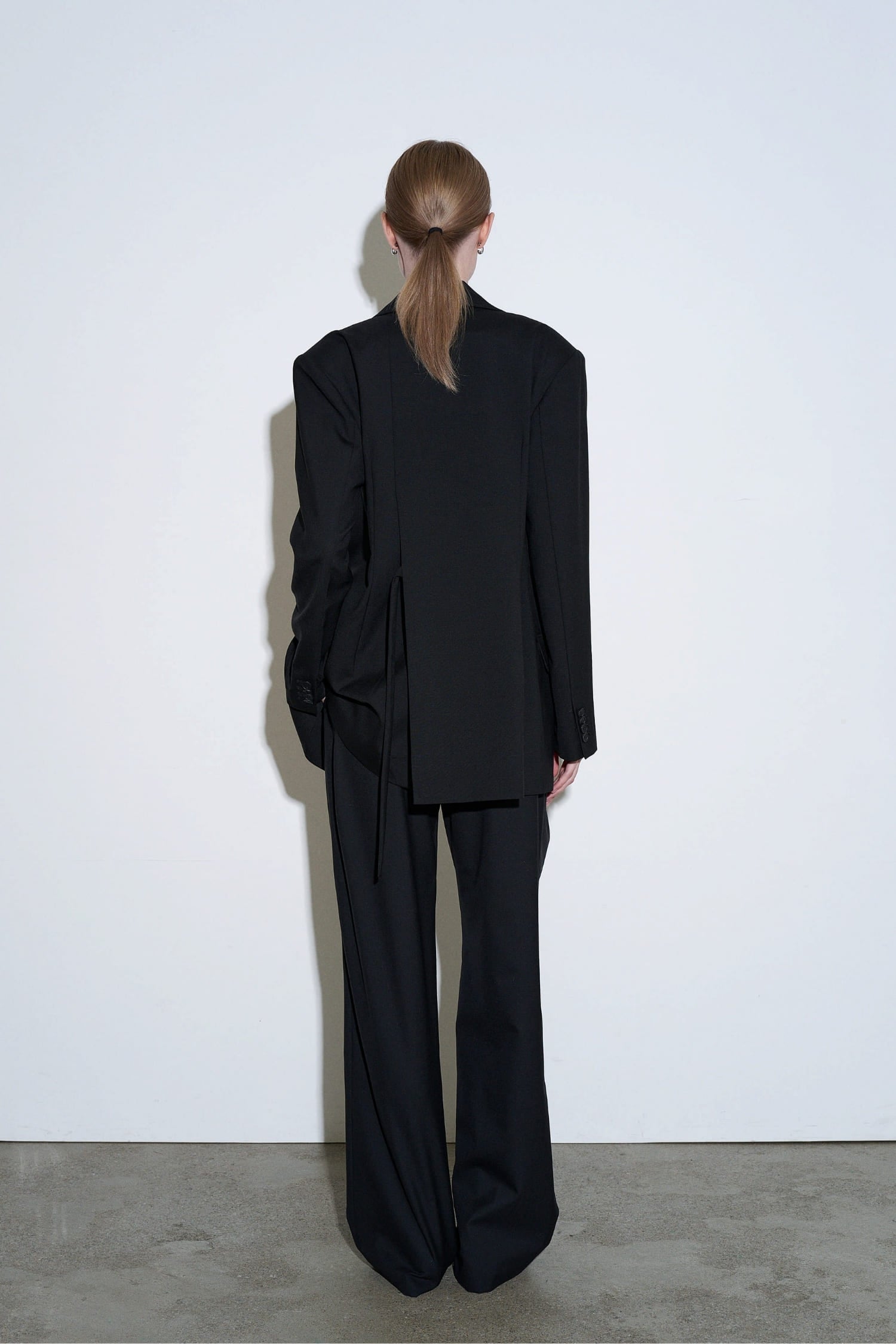 The Loom black high waisted wool trousers back view with tailored waistband and fluid drape