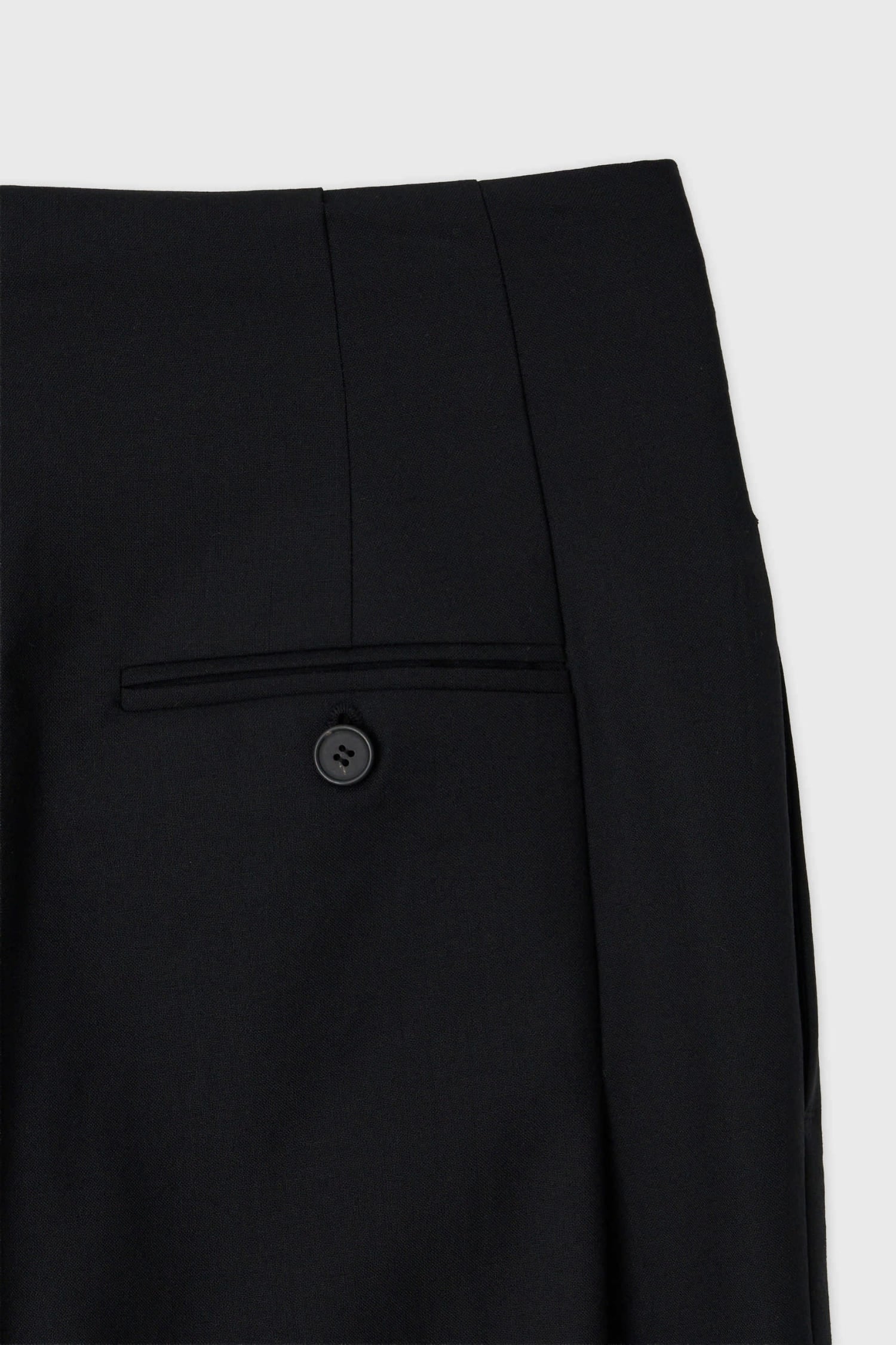 Detail of back welt pocket and button on The Loom black high waisted wool trousers