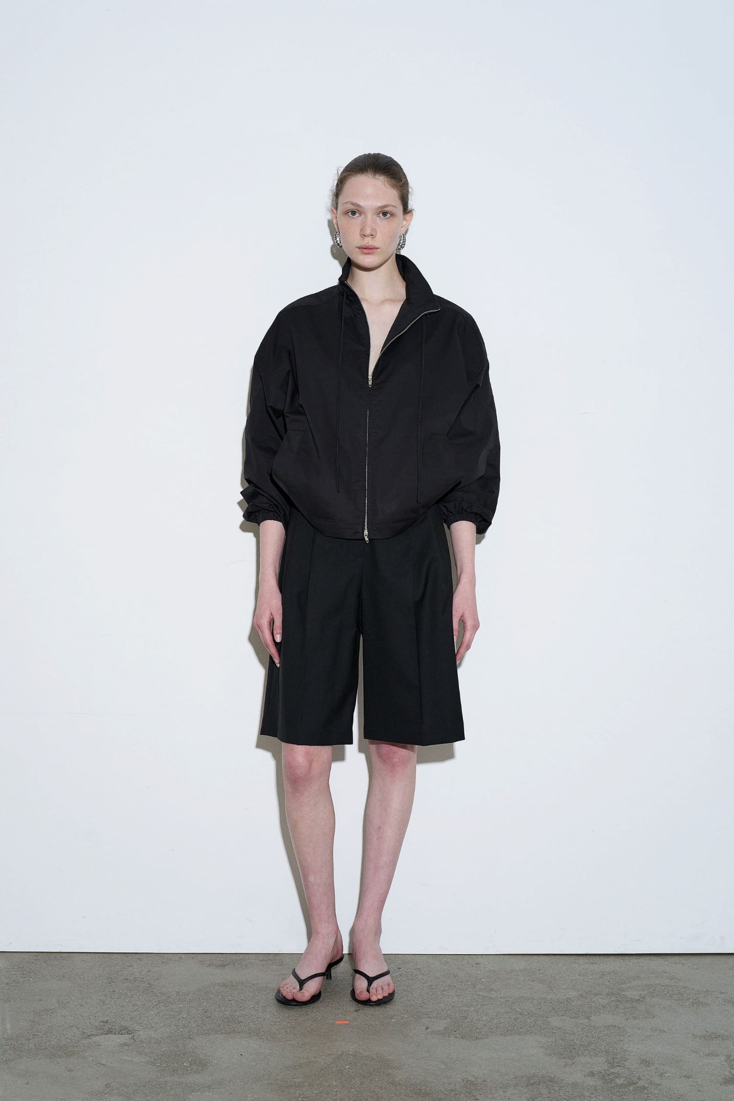 The Loom black summer wool tailored shorts front view with pleated detail and knee length silhouette