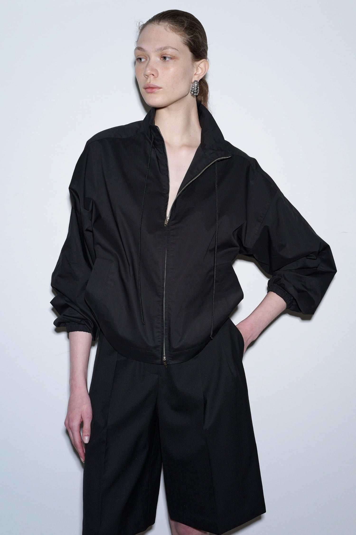 The Loom black summer wool shorts close-up showing front zipper detail and voluminous sleeves styling | hover