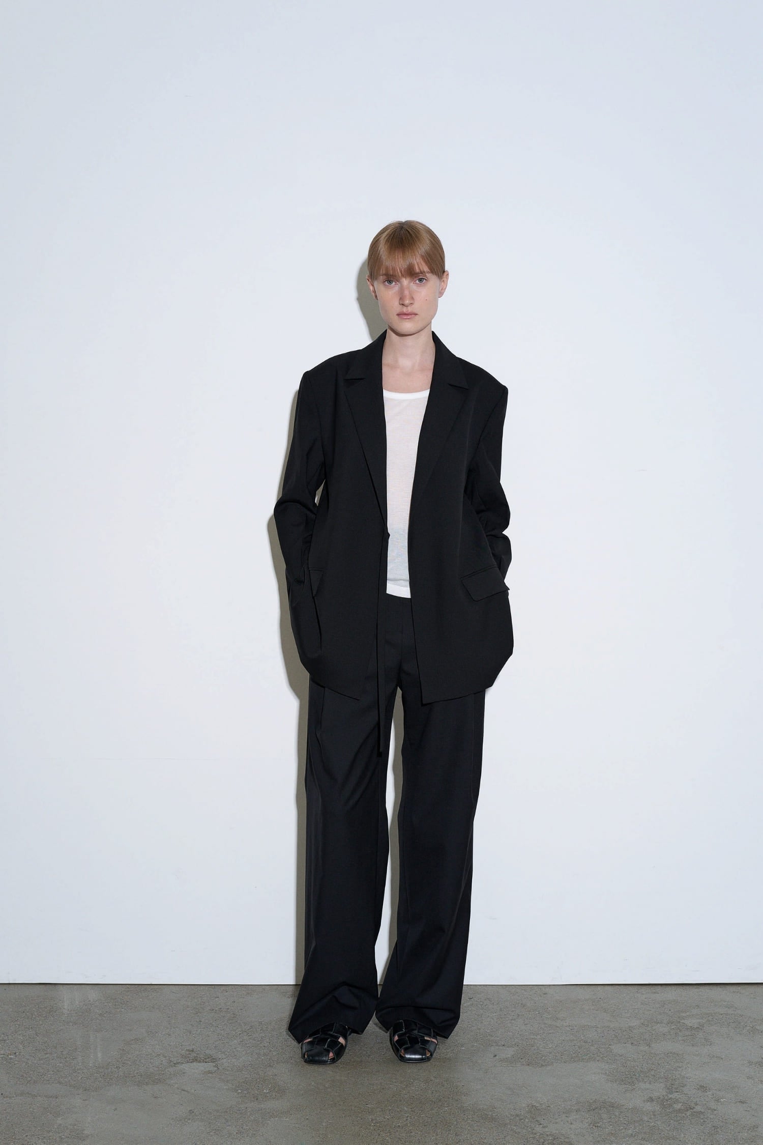 The Loom black wool tie jacket front view with tailored silhouette and side fastening detail